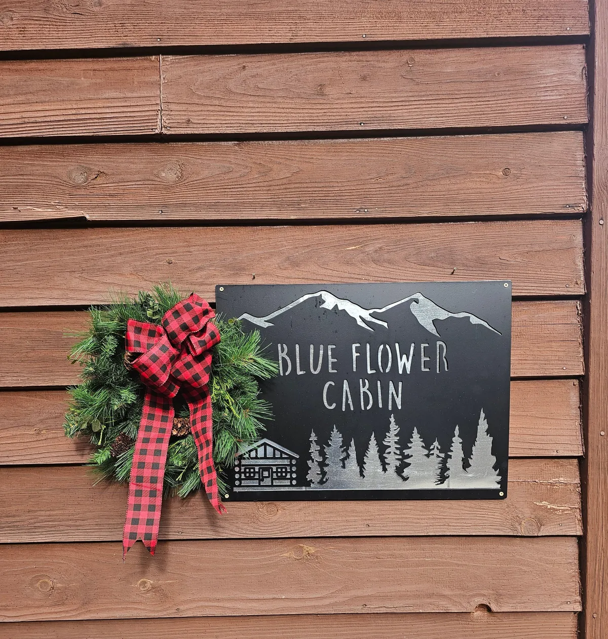 The image displays the cabin's exterior, featuring a welcoming sign, a festive wreath, and a backdrop of mountain silhouettes. The cozy ambiance is evident, suggesting a perfect retreat for families to gather indoors on rainy days. The scene hints at the promise of warmth and connection inside, setting the scene for indoor activities.