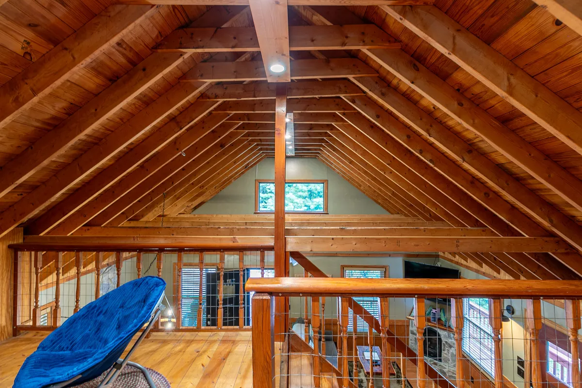 A cozy corner featuring large windows framed by exposed wooden beams and a comfortable blue chair. Through the windows, natural light pours into the space, creating a tranquil atmosphere perfect for unwinding after a day of exploration.